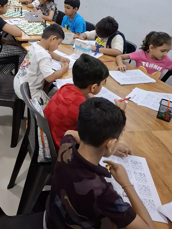 Students solving chess puzzle worksheets at Surat Chess Club, Vesu, for families near Dumas Road