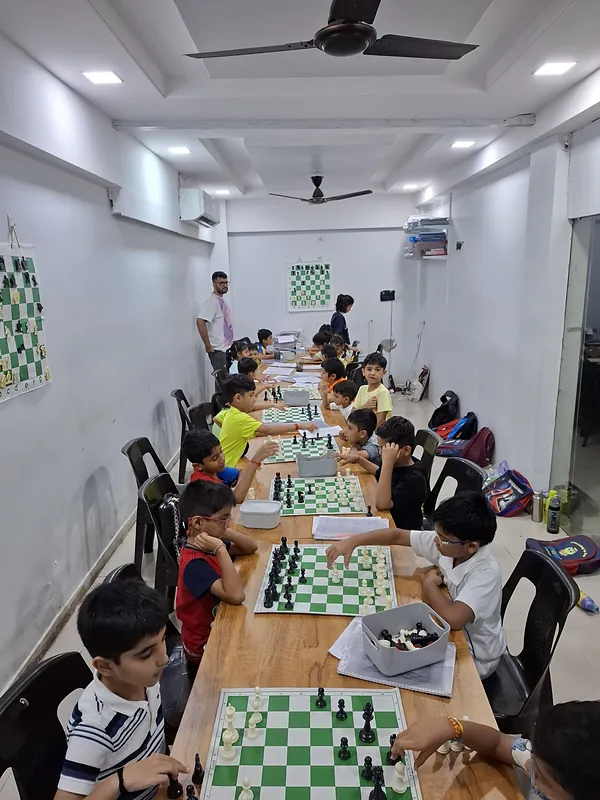 A full evening batch playing practice games along the long tables at Surat Chess Club in Vesu, Surat