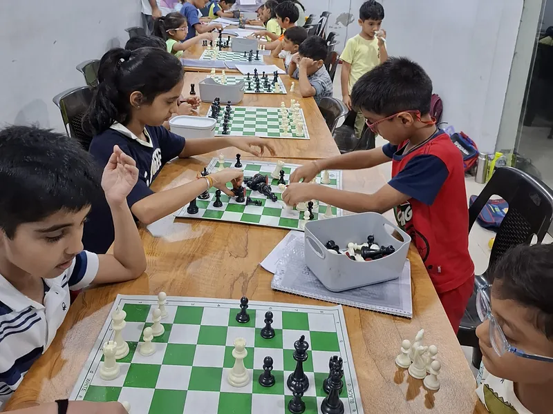 Two students making their moves in a practice game while the rest of the batch plays on