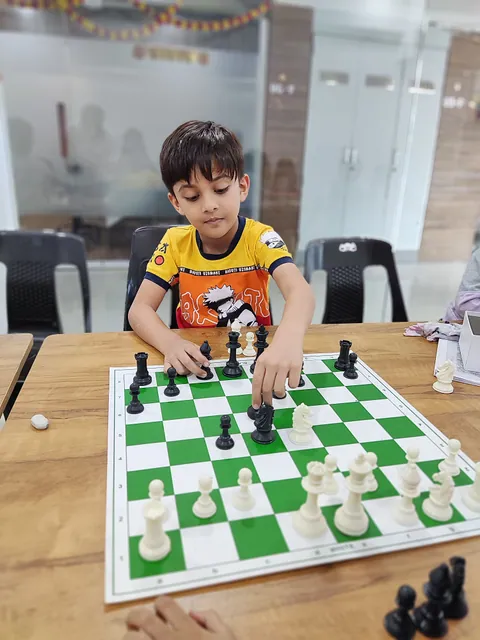 A young boy pushing a pawn forward in a class game
